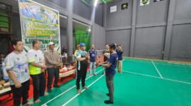 Ketua Panitia Liga Tomandin PBSI Ke-1 Tahun 2026, Rizal Ninggele, ST., menerima piala dari Ketua PBSI Kabupaten Fakfak, Widhi Asmoro Jati.